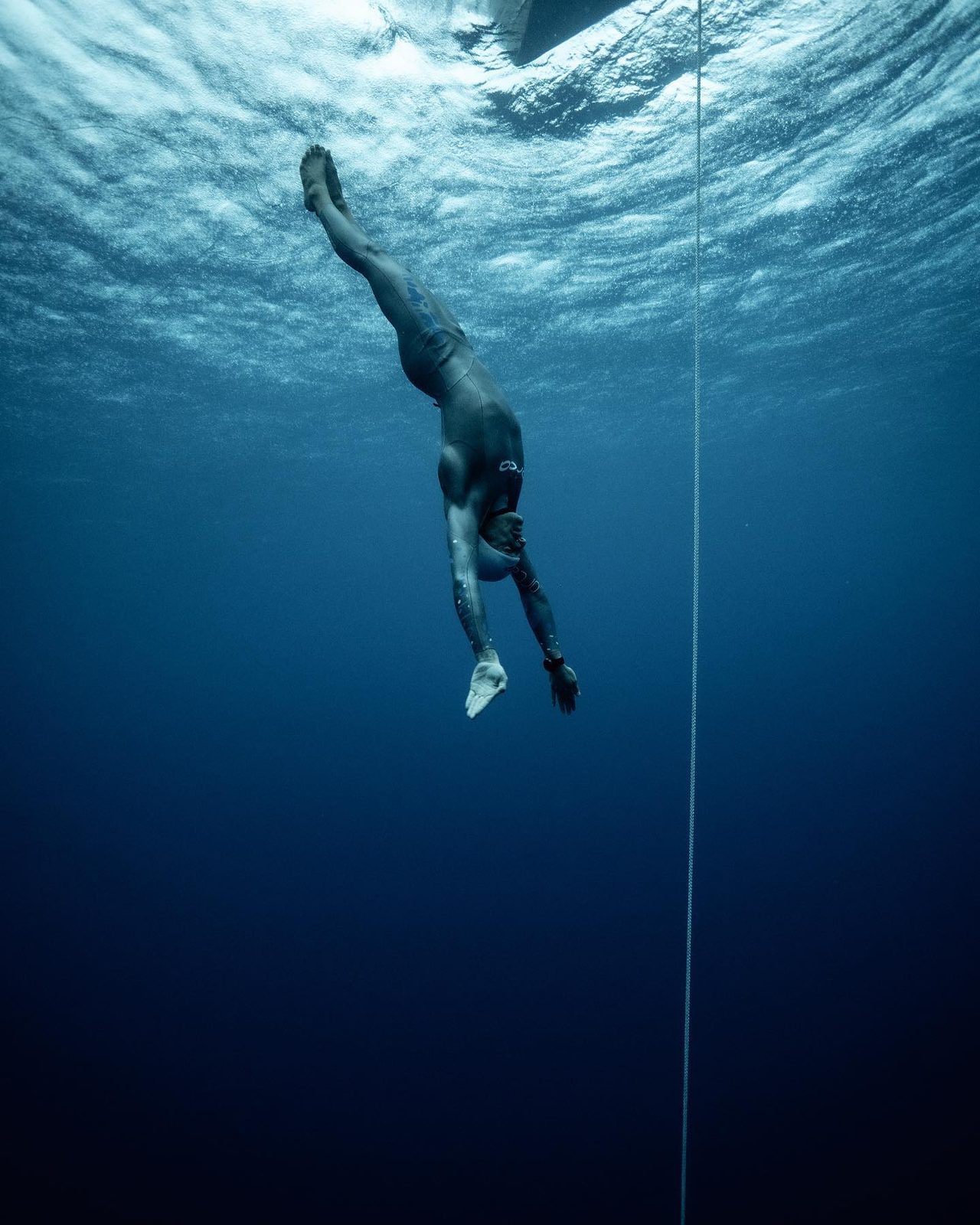 Freediver descending the line into deep blue water
